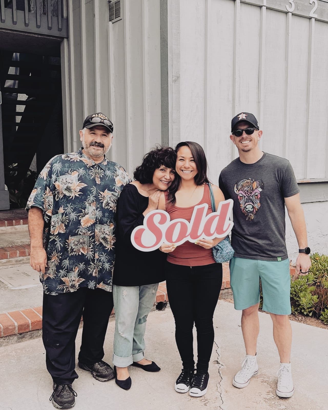 An Ortiz Group seller family celebrating outside their home with a Sold sign on closing day